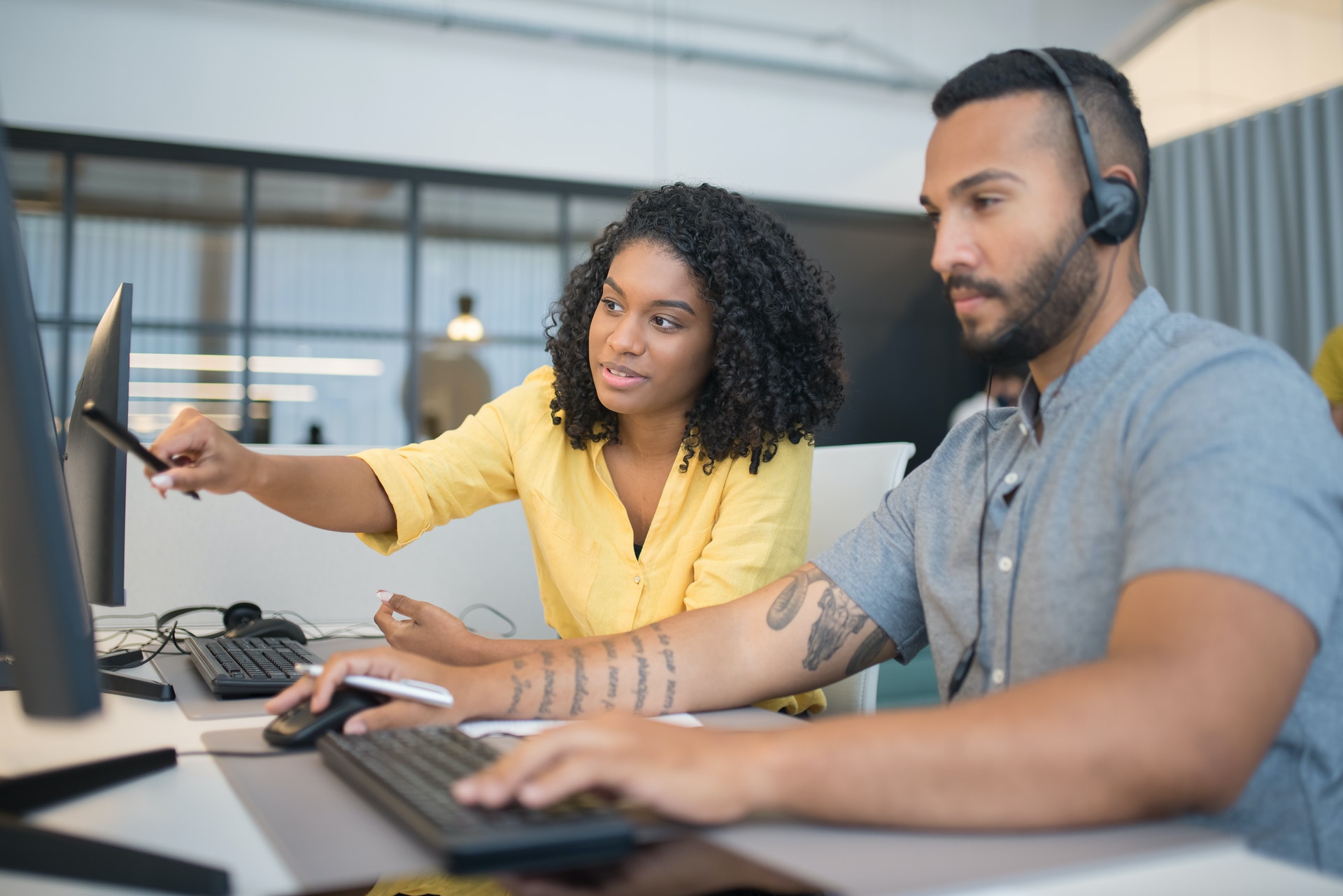 Female employee points at computer next to IT support engineer