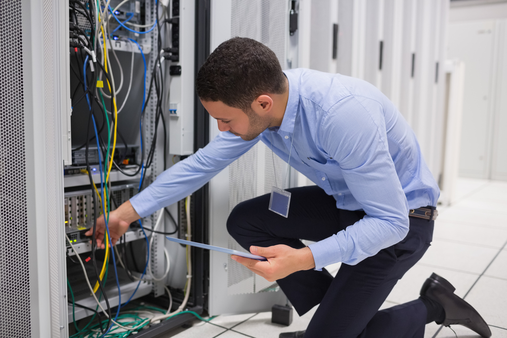 Man checking tablet pc as he is plugging cables into server in data center-Jan-06-2023-09-20-28-3263-AM