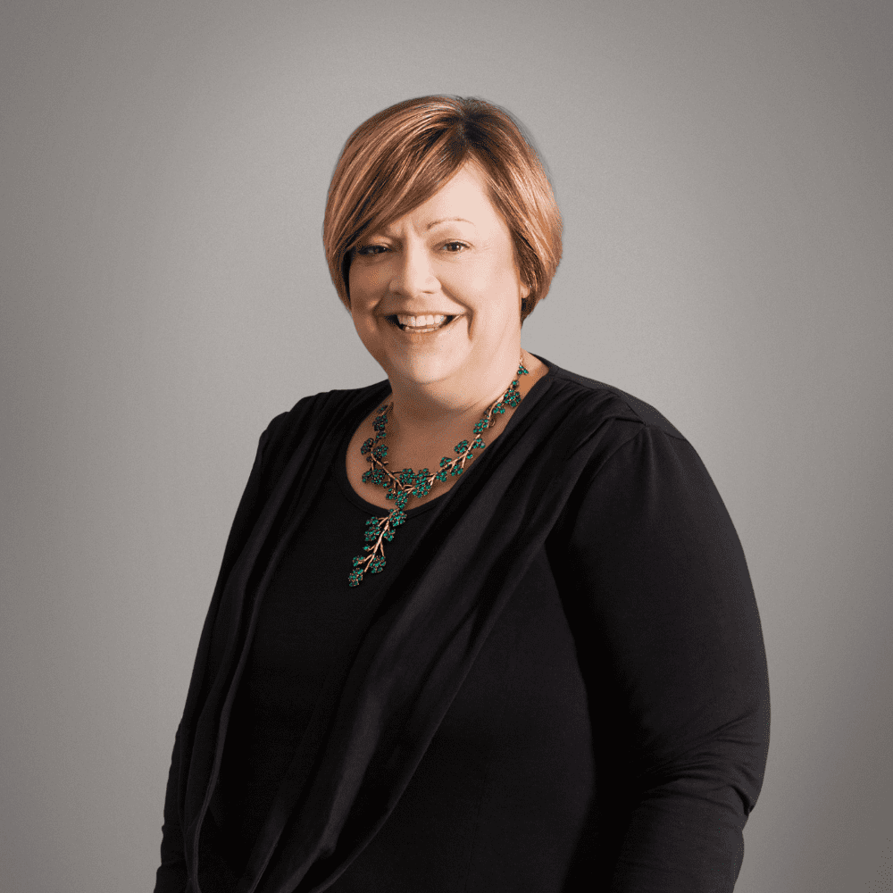 Sara Wilde, MD of Influential wearing a black jacket and elaborate green necklace