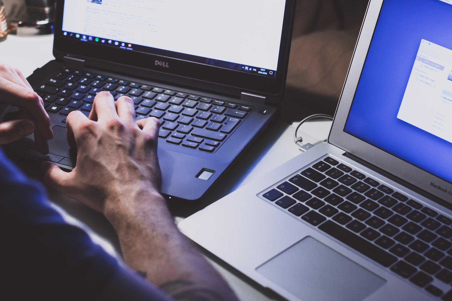 A man working on two laptop computers