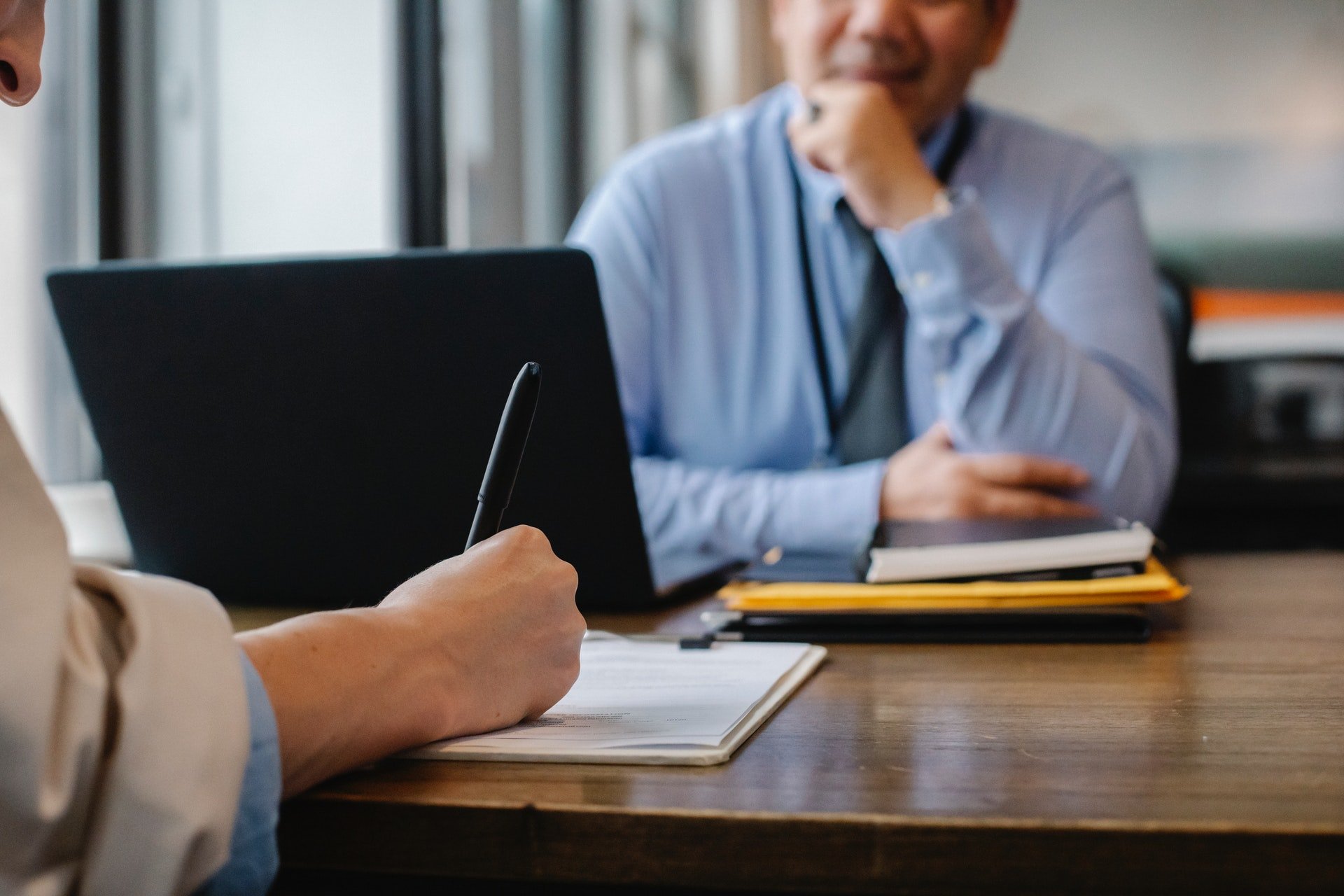 Woman writing notes during business meeting with man